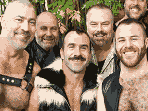Photograph of a group of smiling gay bears in leather vests.